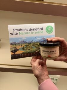 hands holding a jar of hummus
