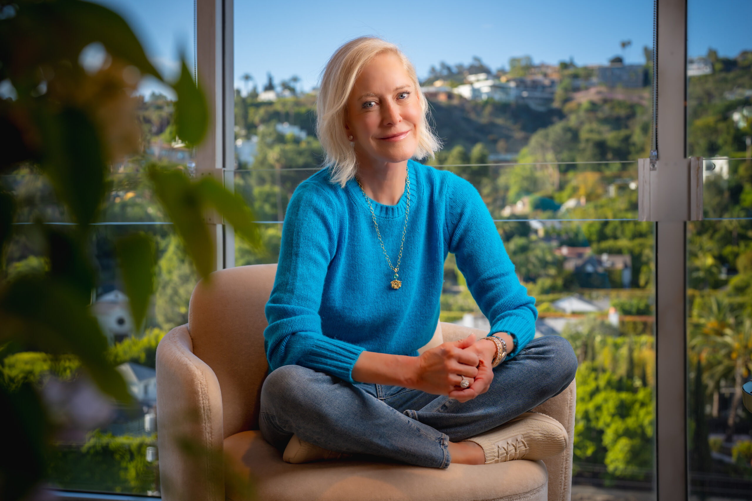Wendy Schmidt in blue sweater sitting cross legged on a chair